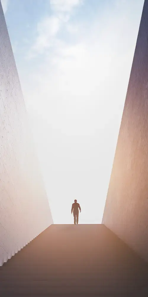Person am Ende einer Treppe, steht oben vor dem Sonnenlicht
